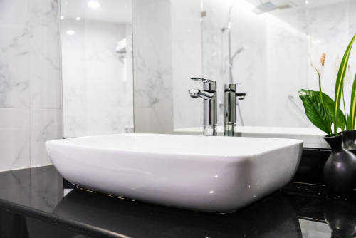 modern-bathroom-sink-with-mirror-and-black-countertop Modern white vessel sink on a black countertop with chrome faucet in a tiled bathroom