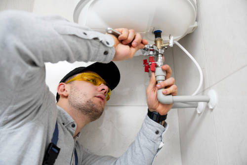 plumber-repairing-water-heater-valves-in-bathroom Professional plumber working on water heater pipes and valves with tools</p>
<p>